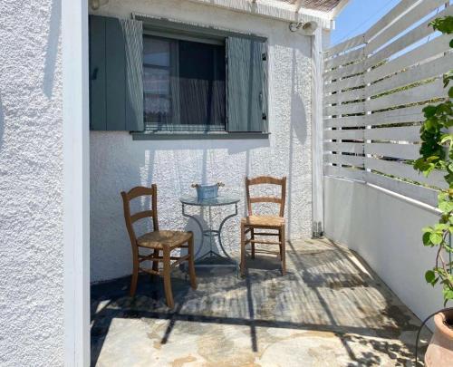 - deux chaises et une table sur une terrasse couverte dans l'établissement Ληγάτο Cottage House, à Áyios Pétros
