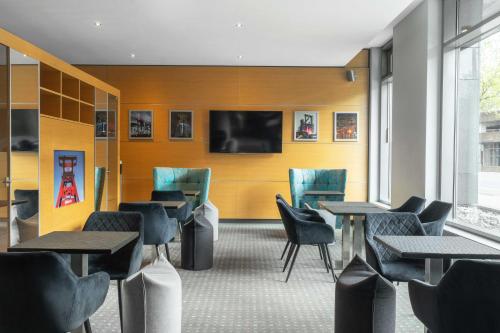 a restaurant with tables and chairs and a flat screen tv at Ramada by Wyndham Essen in Essen