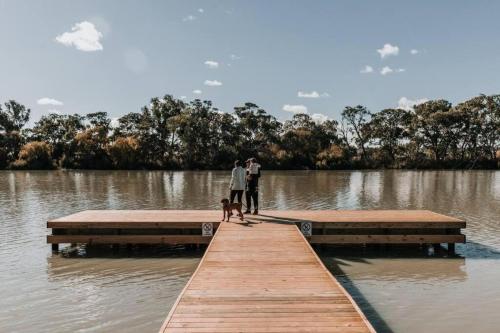 two people and a dog on a dock in a lake at Long Island Retreat - Pelican in Murray Bridge
