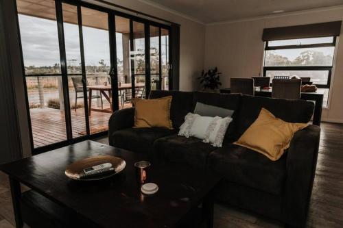a living room with a black couch and a table at Long Island Retreat - Pelican in Murray Bridge