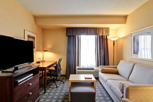a hotel room with a couch and a desk and a television at Homewood Suites by Hilton Toronto Mississauga in Mississauga