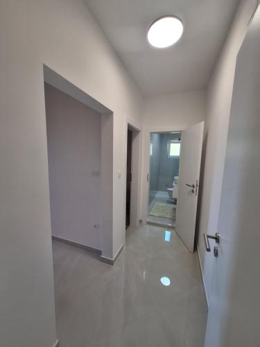 a white hallway with a door and a bathroom at Novouređeni apartman Marko, Kampor - Rab in Rab