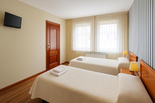 Una habitación de hotel con dos camas y un televisor. en Pension Gelin, en Carrizo de la Ribera