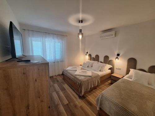 a bedroom with two beds and a flat screen tv at Novouređeni apartman Marko, Kampor - Rab in Rab
