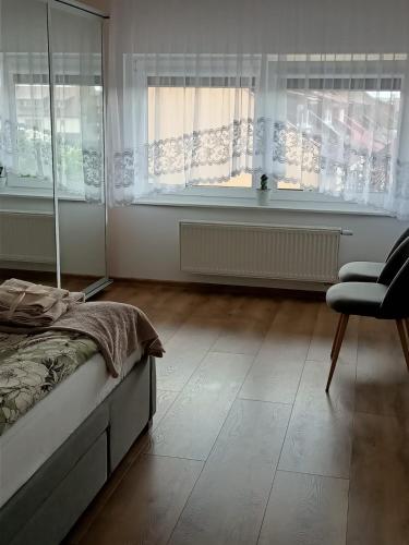 a bedroom with a bed and a chair and windows at Anyżowy Zakątek w Gdyni in Gdynia