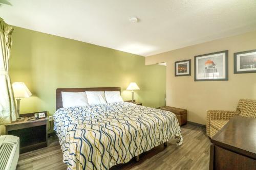 a hotel room with a bed and a chair at Deluxe Inn & Suites By OYO Miami OK in Miami