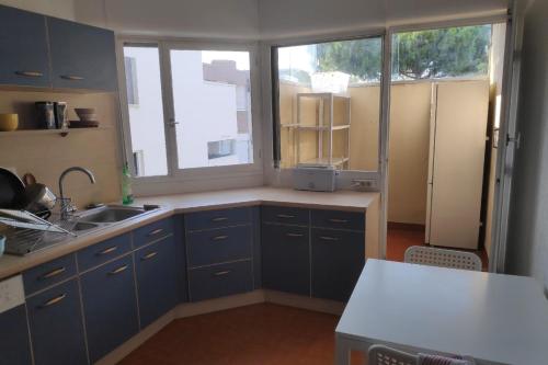 une cuisine avec des armoires bleues, un évier et une fenêtre dans l'établissement Family apartment for 10 people with balcony, à Montpellier