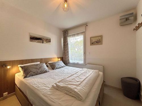 une chambre avec un lit avec des draps blancs et une fenêtre dans l'établissement Appartement 3 pièces avec jardin privatif - La Baule Centre - FR-1-245-102, à La Baule