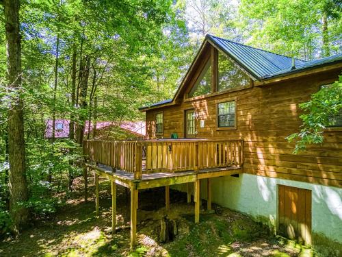 a log cabin with a deck in the woods at Adalynn's Mountain Retreat-Hot Tub, Cozy Cabin Retreat in the Smokies Comfort & Fun for All in Pigeon Forge