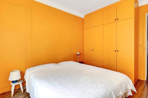 - une chambre avec des murs jaunes et un lit blanc dans l'établissement Charmant 70m2 pour 4 pers Rue de Crussol Paris, à Paris