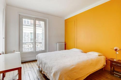 - une chambre avec un lit et un mur jaune dans l'établissement Charmant 70m2 pour 4 pers Rue de Crussol Paris, à Paris