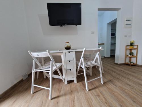 a white table with two chairs and a tv on a wall at Casa Felicita Garden Porto Frailis in Àrbatax