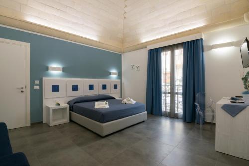 a blue bedroom with a bed and a window at Pharos in San Vito lo Capo