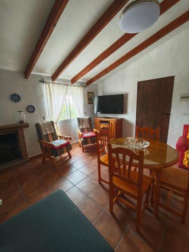a living room with a table and chairs and a tv at Casa Rural Martín in Canillas de Aceituno