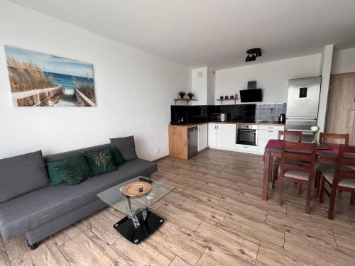un soggiorno con un divano, un tavolo e una cucina di Apartament Aquatower a Reda
