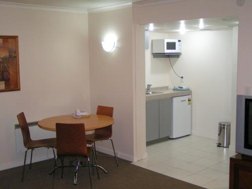 a room with a table and chairs and a kitchen at Admirals Motor Inn in Nelson
