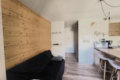 - un salon avec un canapé noir et un mur en bois dans l'établissement Apartment with balcony 800 meters from the sea, à Canet