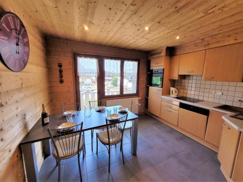 une cuisine avec une table, des chaises et une horloge dans l'établissement Appartement cosy, 3 balcons, plein centre, proche pistes - idéal 5-6 pers. - FR-1-598-101, aux Gets