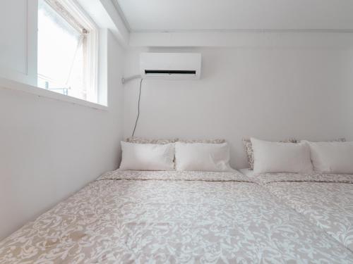 a bed in a white room with a window at SeogyoHueStay in Seoul