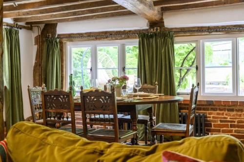 ein Esszimmer mit Tisch und Stühlen und Fenstern in der Unterkunft Cruck Cottage in Fordingbridge