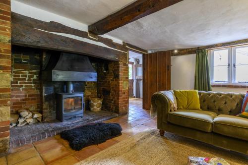 ein Wohnzimmer mit Couch und Kamin in der Unterkunft Cruck Cottage in Fordingbridge