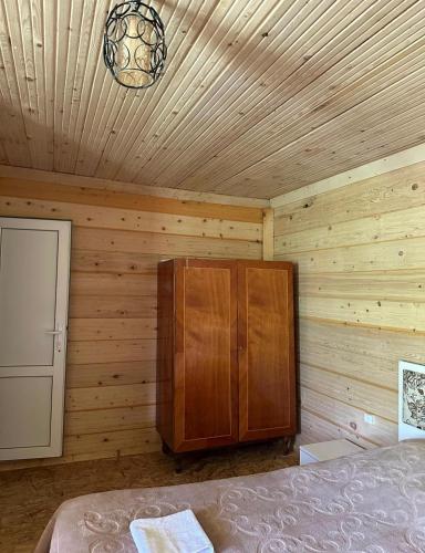 a bedroom with a bed and a wooden wall at Qvis Sakhli in Tvebishi