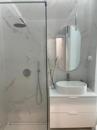 a white bathroom with a sink and a mirror at Apartament Echo Park in Olecko