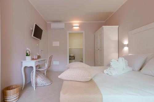 a white bedroom with a white bed and a table at La Rosa dei Venti Guesthouse in Villasimius