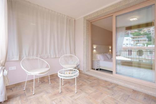 two chairs and a table in a room with a bedroom at La Rosa dei Venti Guesthouse in Villasimius