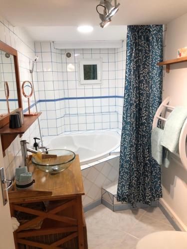 une salle de bain avec une baignoire et un lavabo dans l'établissement Appartement Rez de jardin 1 à 4 pers - 2 chambres, à Collobrières