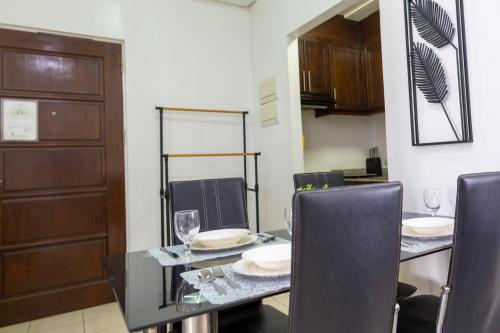 Un comedor con una mesa de cristal y sillas. en Pedersen Condo, en Cebú