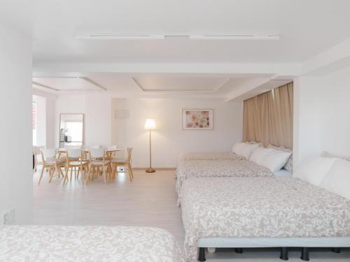 a hotel room with two beds and a dining room at SeogyoHueStay in Seoul
