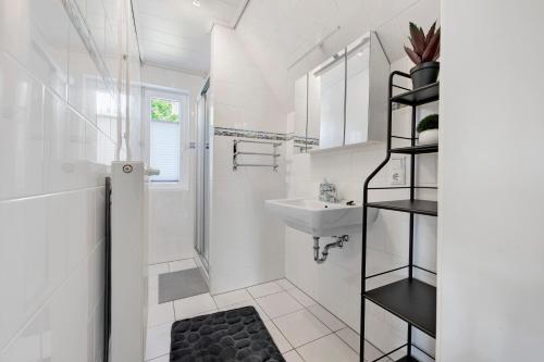 a white bathroom with a sink and a mirror at Ferienhaus Neumann in Heide