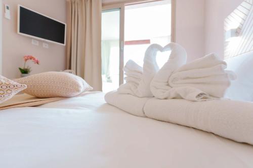 a bed with two towels in the shape of swans at La Rosa dei Venti Guesthouse in Villasimius