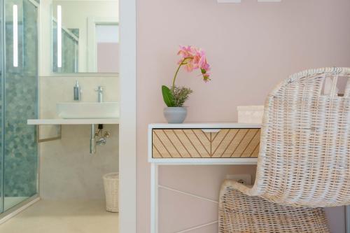 a wicker chair in a bathroom with a sink at La Rosa dei Venti Guesthouse in Villasimius