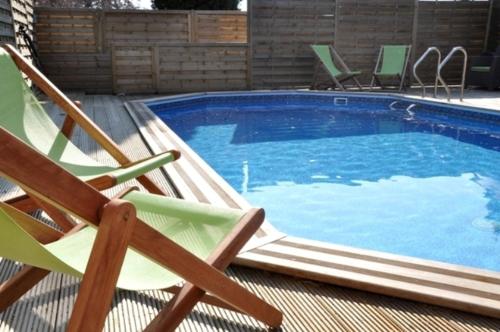 - une piscine avec 2 chaises longues à côté dans l'établissement Logis Hôtel Saint Paul, à Vivy