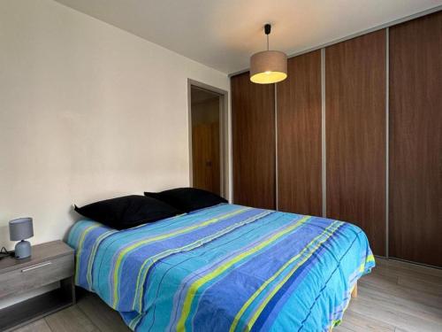 - une chambre dotée d'un lit avec une couverture rayée bleue et jaune dans l'établissement Le logis du chevalier saint-jean, au Puy-en-Velay