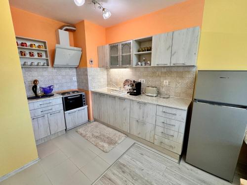a kitchen with white cabinets and an orange wall at Sea View Apartment in Aurora Complex, Steps from the Beach in St. St. Constantine and Helena