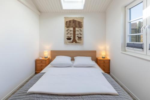 a bedroom with a bed with white sheets and a window at Schimmelreiter in Simonsberg