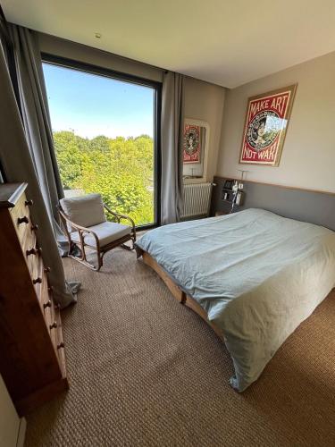 - une chambre avec un lit, une chaise et une grande fenêtre dans l'établissement Caen, très jolie maison à deux pas du mémorial, à Caen