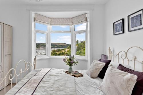 a white bedroom with a bed and a window at River Retreat in Kingswear