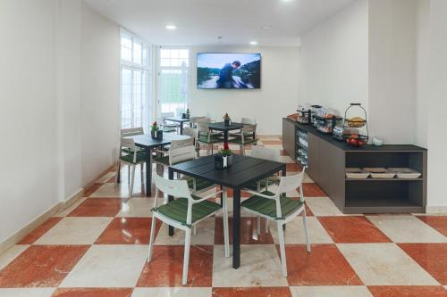 a dining room with tables and chairs and a tv at STAR BAY Hotel in Calafell
