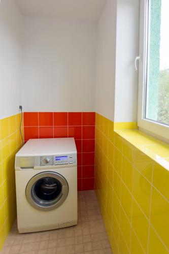 a washer and dryer in a bathroom with yellow and red tiles at Dream Hostel Carpathians Rakhiv in Rakhiv