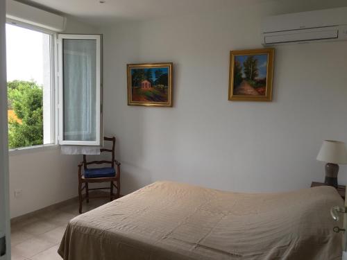une chambre avec un lit et deux tableaux au mur dans l'établissement Maisonnette 2 minutes pied plage, à Grosseto-Prugna