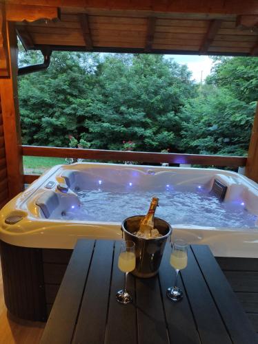 a tub with a bottle of champagne and two wine glasses at Luxury Love Cottage Spa- privatni jacuzzi &sauna , mir i privatnost in Velika Gorica