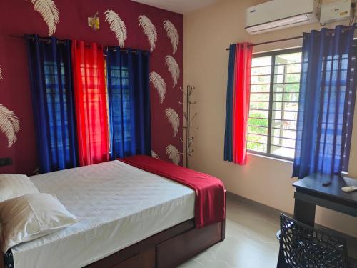 a bedroom with red and blue curtains and a bed at Marari beach homestay in Vayalār
