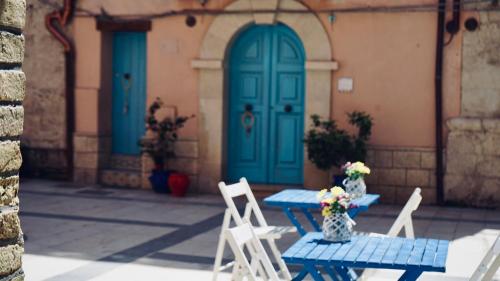 two tables with chairs and a blue door at Antica Dimora San Girolamo in Licata