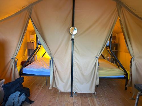 a tent with two beds in it on a wooden floor at Domaine de l'Atrée - Tente Maasaï Poyaudine in Saint-Martin-des-Champs