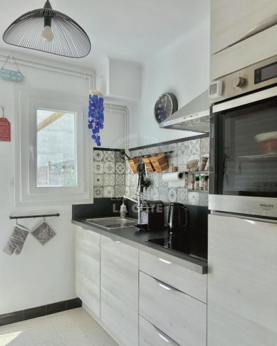 une cuisine avec un évier et un micro-ondes dans l'établissement Maison Sable & Mer, à Merlimont