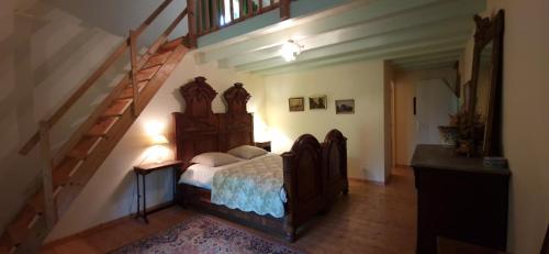 - une chambre avec un lit doté d'une tête de lit en bois et d'un escalier dans l'établissement Ferme de la Haute Maison Maison d hotes, à Saint-Loup-de-Naud